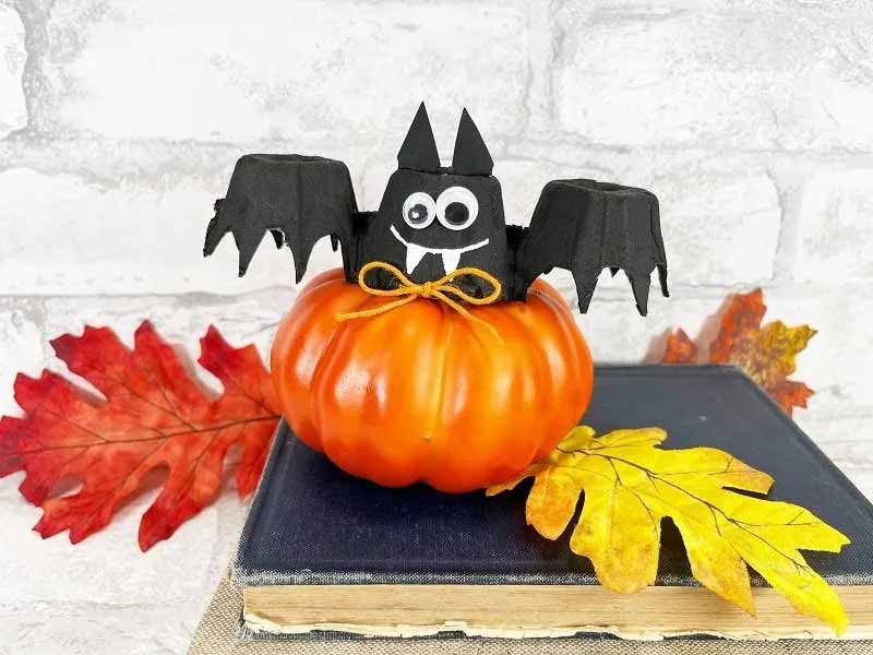 a pumpkin with bat on top made with egg cartons