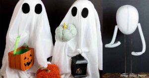 Two figures are dressed as ghosts with white sheets and black eye holes. One ghost holds an orange pumpkin bucket, and the other ghost holds a lantern and a small, stuffed pumpkin. Positioned to their right is a ghost costume on a foam head and armature.