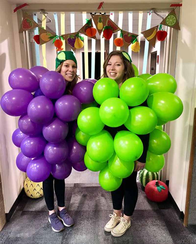 2 girls with purple and green grape costumes with balloons