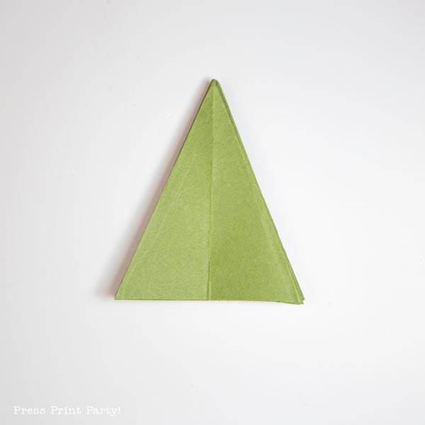 A green origami triangle, resembling a folded paper Christmas tree, rests on a white background.