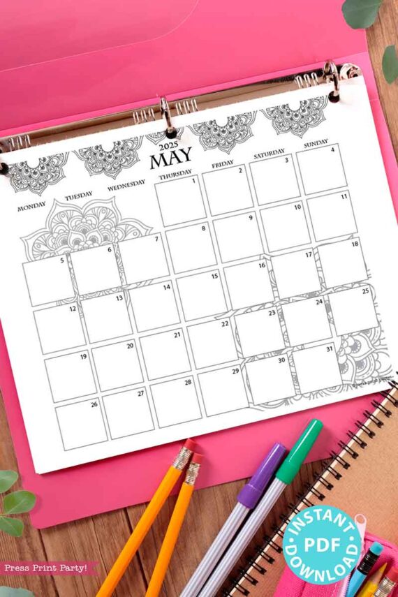 The desk scene showcases a 2025 One Page Calendar at-a-glance Printable Mandala, embellished with intricate designs, enclosed in a pink binder. Adjacent to it are vibrant pens, a spiral notebook, and green leaves. A turquoise sticker announces "Instant PDF Download.