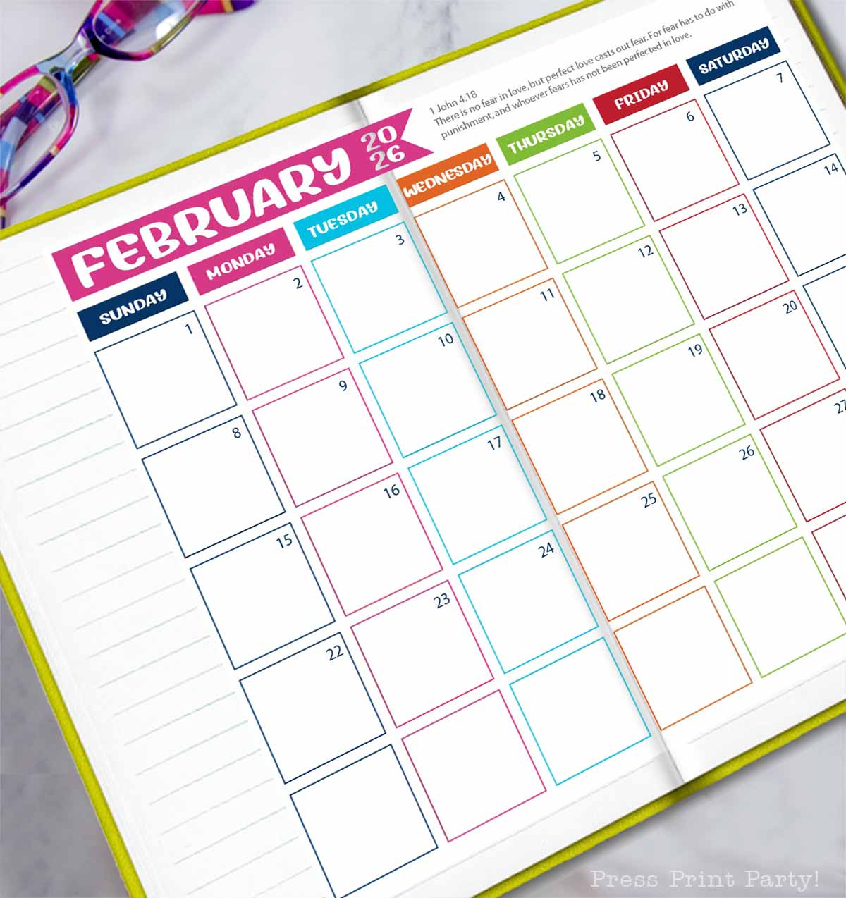 Open planner displaying a colorful, undated February 2026 calendar with blank boxes for each day. Glasses rest at the top left corner, and lined note pages are visible on the left side—perfect for your free 2026 calendar printable needs.