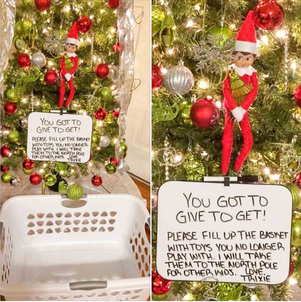 A Christmas tree with red and silver ornaments. An elf toy is perched on a branch above a white sign that reads, "You got to give to get! Please fill up the basket with toys you no longer play with..." A white basket is placed below.