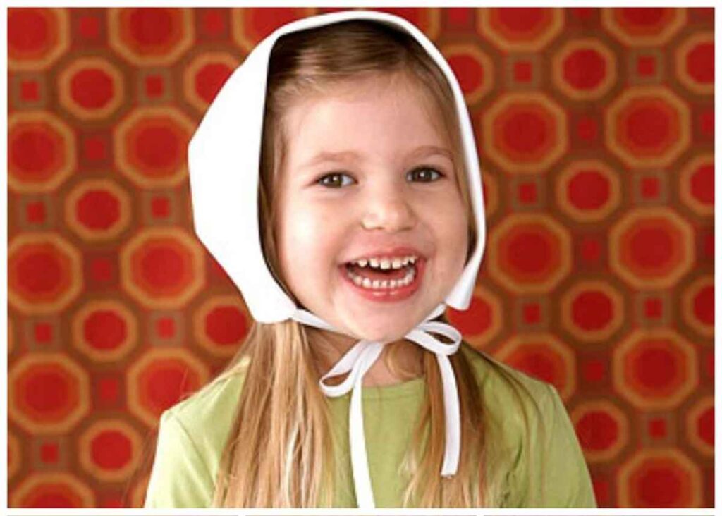 A young girl with long hair smiles brightly, wearing a white bonnet and a green shirt. The background features a retro orange and red geometric pattern.
