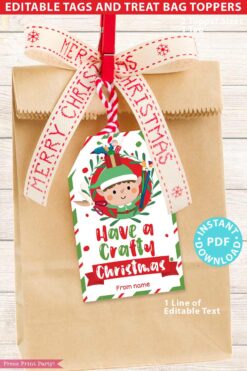 The Mrs. Claus Bakery Christmas Treat Bag Topper & Tag features a brown paper bag adorned with a festive red and white ribbon and a tag showcasing an elf carrying presents. The tag reads "Have a Crafty Christmas" with the option to add a personalized name, while the bottom right corner displays the "Instant PDF Download" text.