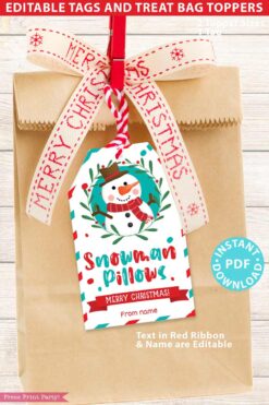 A brown paper gift bag adorned with a red Merry Christmas ribbon and a festive snowman tag, named "Mrs. Claus Bakery Christmas Treat Bag Topper & Tag." The tag includes the phrase "Snowman Pillows, Merry Christmas!" along with options for editable text. An "Instant PDF Download" label is clearly displayed.
