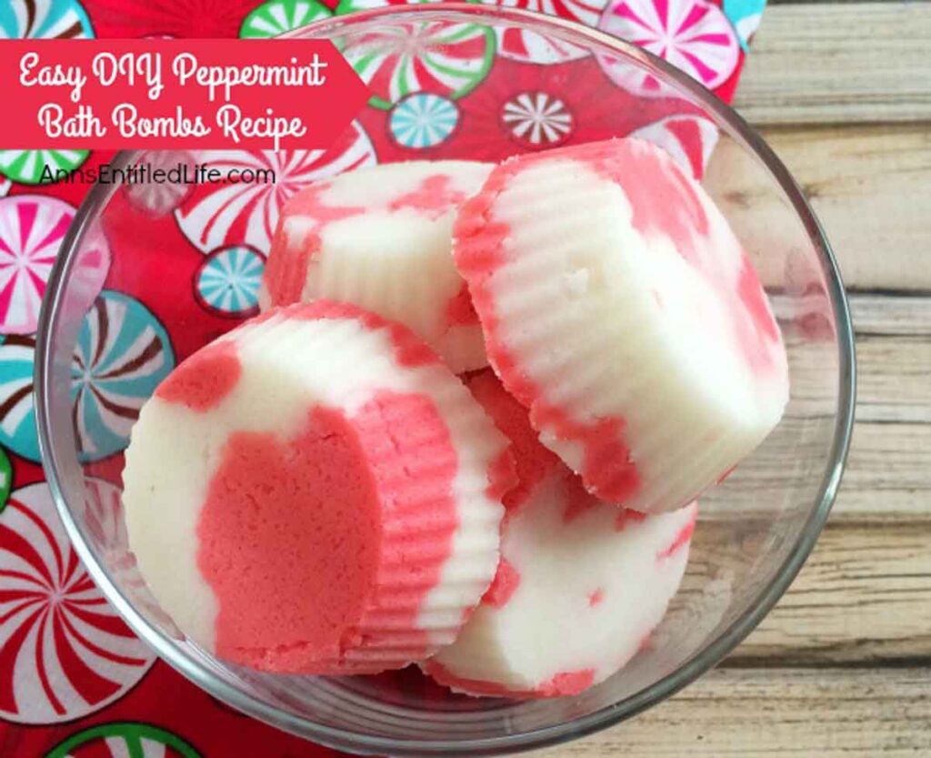 A glass bowl filled with pink and white peppermint bath bombs sits on a colorful peppermint-patterned fabric, perfect for Christmas crafts for teens. The text reads "Easy DIY Peppermint Bath Bombs Recipe - Ann's Entitled Life.com.