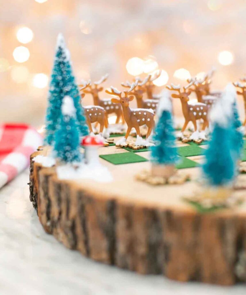 A festive miniature scene perfect for Christmas crafts for teens, featuring reindeer figurines and snow-dusted pine trees on a wooden slab. Warm fairy lights create a cozy background.