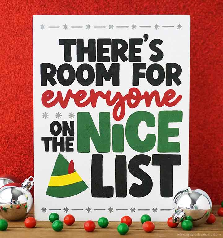 Festive sign with the text "There's room for everyone on the nice list" in bold black, red, and green letters. Decorative elements include small ornaments and colorful candy on a red background.