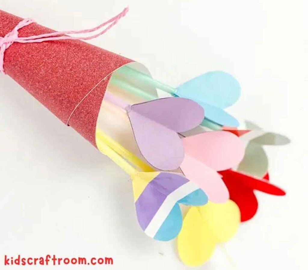 A bouquet crafted from colorful paper hearts, wrapped in glittery red paper and tied with pink string—a perfect piece of Valentine paper crafts. A website URL peeks from the lower left corner, hinting at where this charming creation came to life.