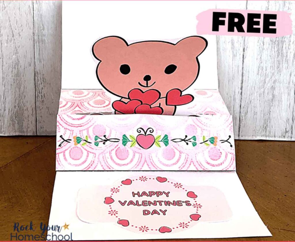 A pop-up Valentine's Day card features a cute bear holding heart shapes, with decorative pink and floral designs. The card is open and reads "Happy Valentine's Day." A "FREE" label is in the top right corner.