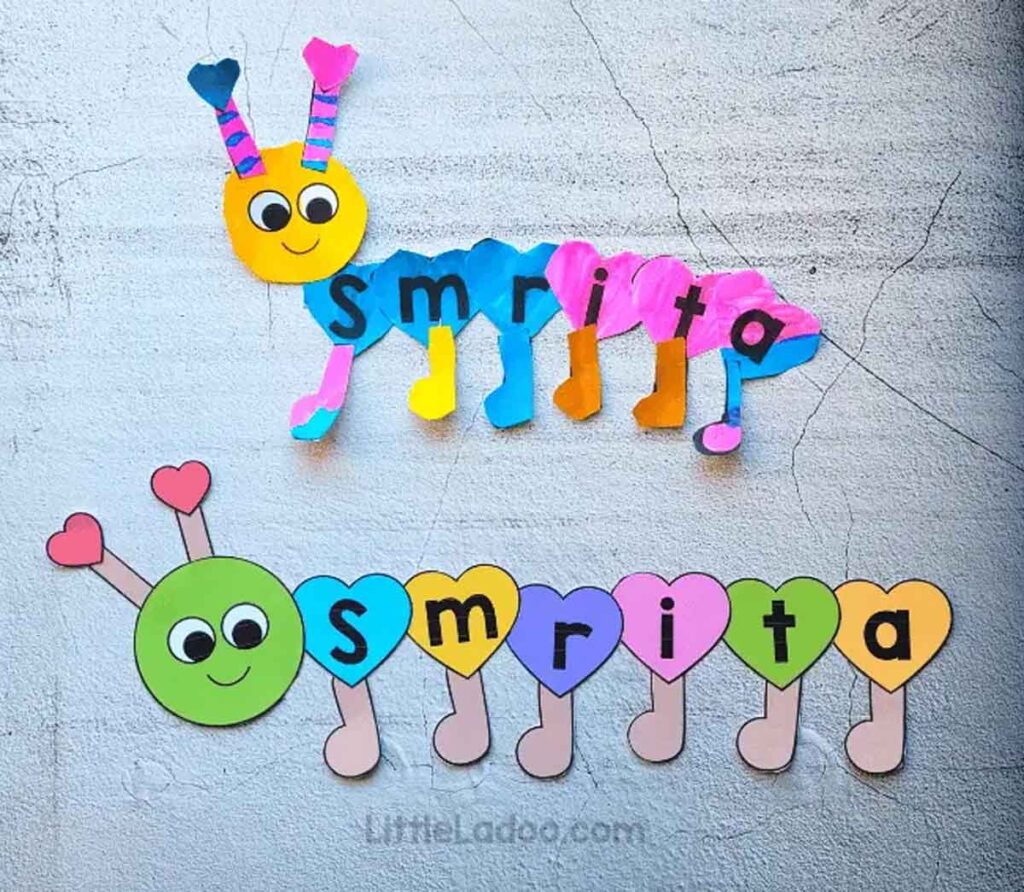 Two vibrant caterpillars, crafted as charming Valentine paper crafts, showcase letters on their segments spelling "Smrita." These colorful creations feature heart-shaped details against a textured background, radiating love and creativity.