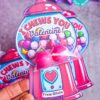A hand holds a colorful Valentine's card shaped like a gumball machine with pink gumballs, reading "I Chews You Valentine!" and signed "From Olivia." Similar cards are seen in the background. Product Name: template (Copy) (Copy).