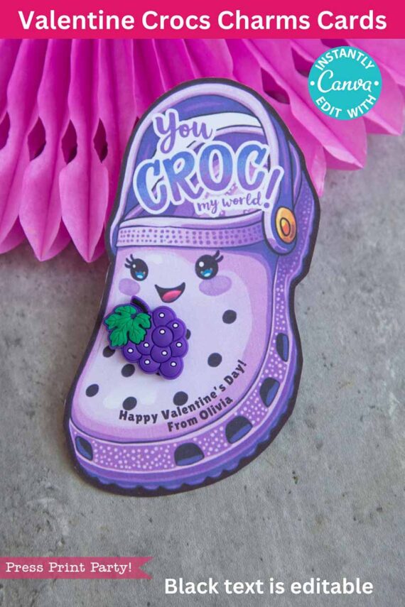 A charming Valentine's card showcasing a smiling purple Croc shoe with eyes and a grape charm, alongside the text "You CROC my world!" It includes "Happy Valentine’s Day! From Olivia" at the bottom, set against a pink honeycomb decorative backdrop.