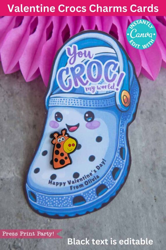 A Valentine's Day card shaped like a blue Croc shoe features a smiling face and reads "You CROC my world!" It includes a giraffe charm and says "Happy Valentine's Day! From Olivia" against a pink background. Product Name: template (Copy) (Copy).