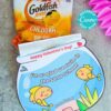 A packet of Goldfish crackers is included with a vibrant fishbowl-shaped Valentine card featuring two cartoon yellow fish and the message, "Happy Valentine's Day! I'm so glad we swim in the same school!.