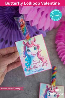 A hand displays the "template (Copy) (Copy)" Valentine's Day card. It features a unicorn with rainbow hair and the message, "Have a magical Valentine's Day," paired with an attached rainbow lollipop. Pink and purple decorations adorn the background.