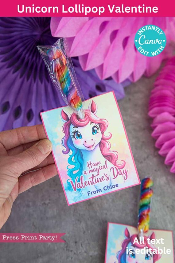 A hand holds a colorful Valentine's card titled "template (Copy) (Copy)," featuring a unicorn with rainbow hair and an attached striped lollipop. The card reads, "Have a magical Valentine's Day" and "From Chloe," set against purple and pink paper decorations.
