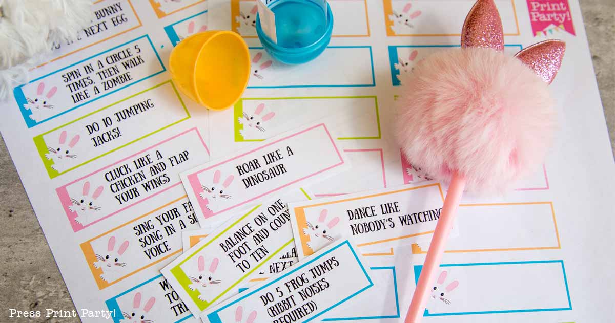 A collection of vibrant Easter-themed activity cards perfect for an Easter egg hunt. Each card features playful tasks like "Roar like a dinosaur" or "Spin in a circle five times." A fluffy pen with pink bunny ears and an open plastic egg accompany the set, inviting endless fun.