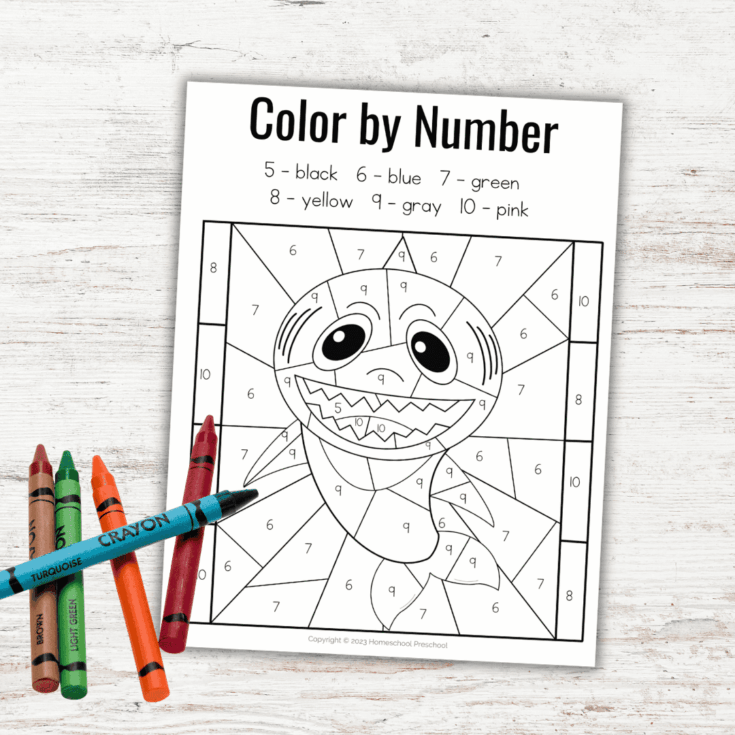 A color-by-number worksheet featuring a smiling worm with numbers in each section. There are four crayons (orange, green, turquoise, and red) beside the worksheet on a white wooden surface.