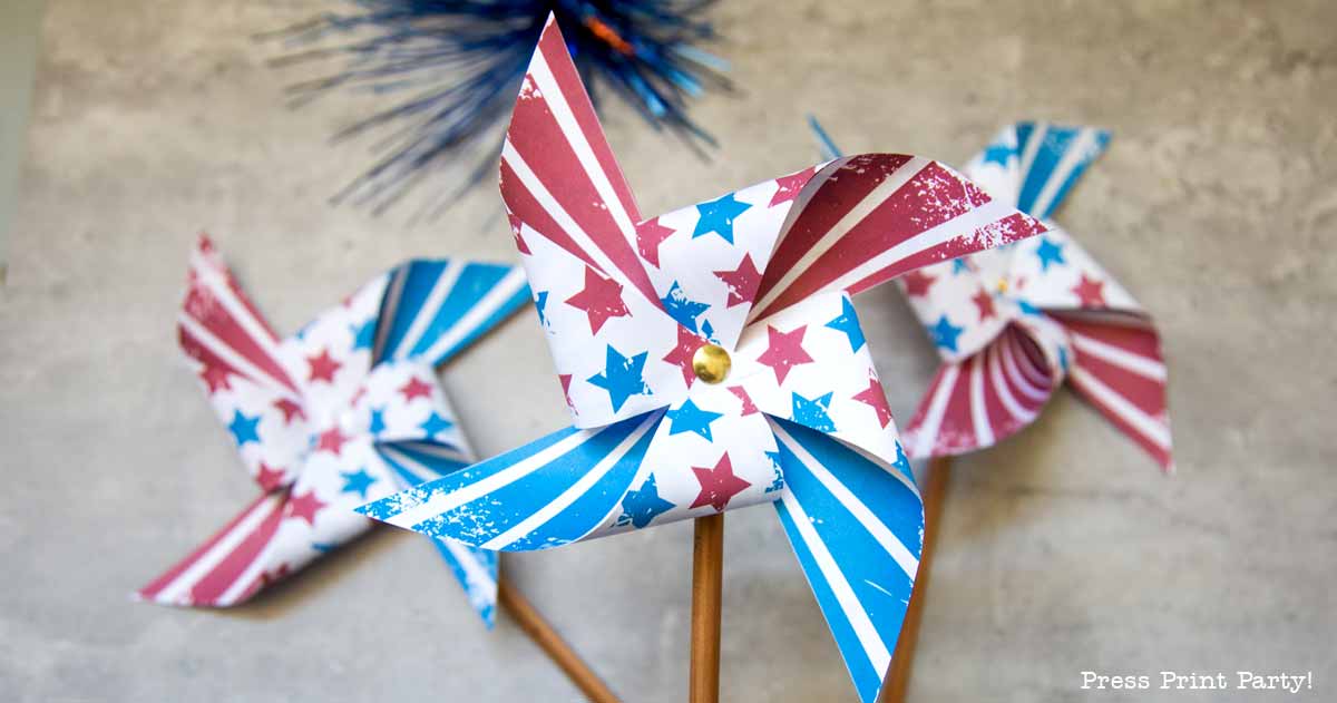 Three patriotic pinwheels with red, white, and blue star and stripe patterns on wooden sticks, arranged for a festive, patriotic celebration.