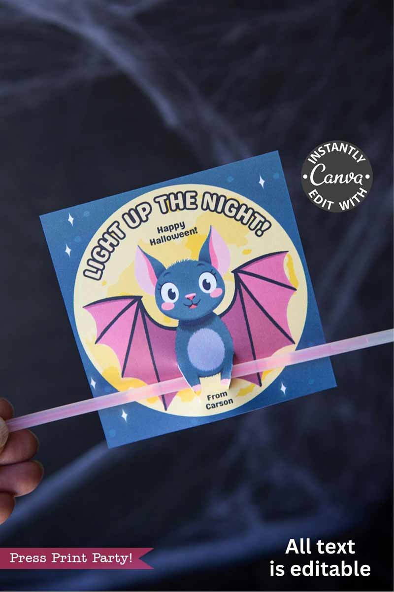 A hand holds the Cute Ghost Halloween Gift Card Holder, a Canva-editable card designed to hold a glow stick. It features a cute cartoon bat with pink wings and the phrase โLight Up the Night! Happy Halloween! From Carson.โ.