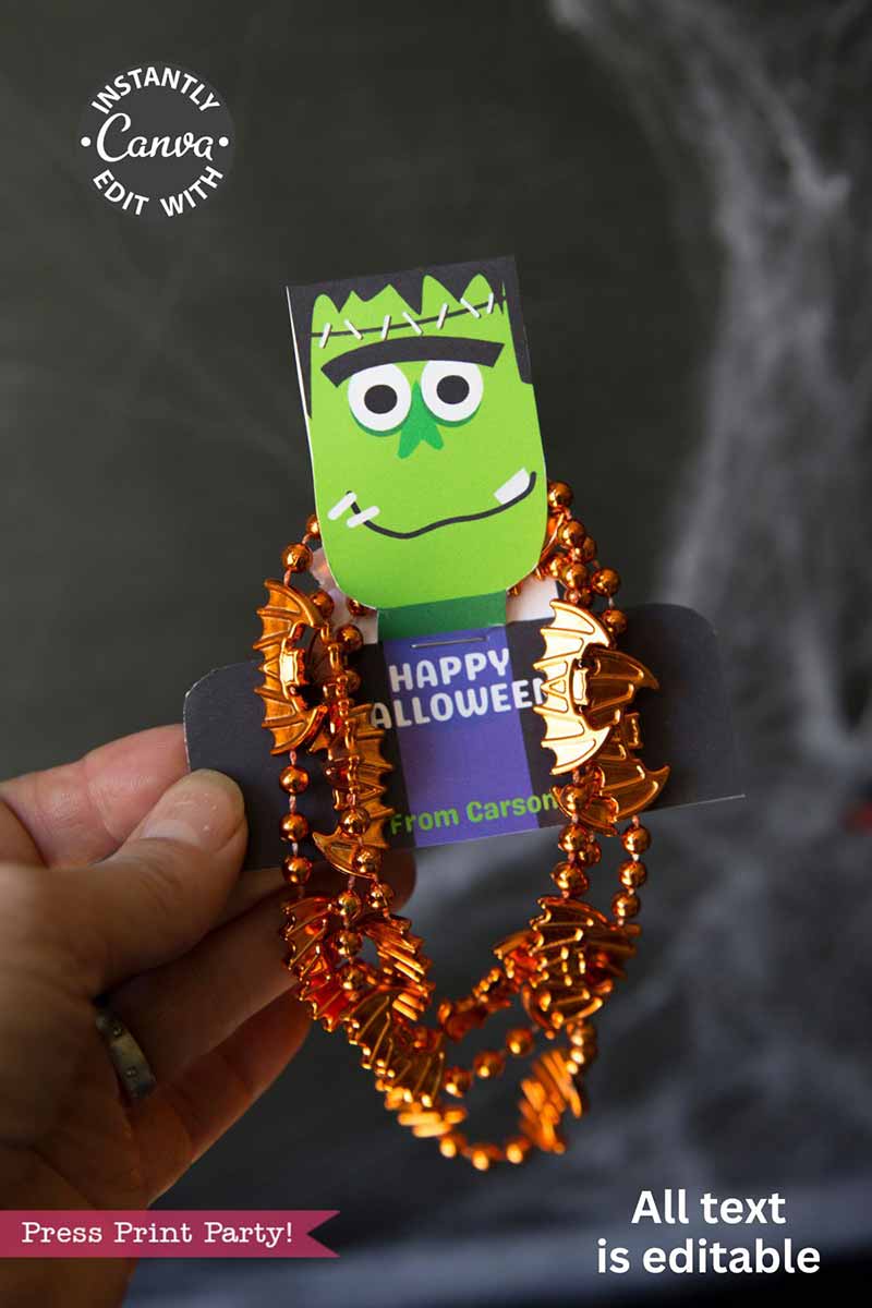 A hand holds the Cute Ghost Halloween Gift Card Holder featuring a cartoon Frankenstein face, orange bat beads, Canva sticker, “Happy Halloween,” “From Carson,” and a note: "All text is editable.
