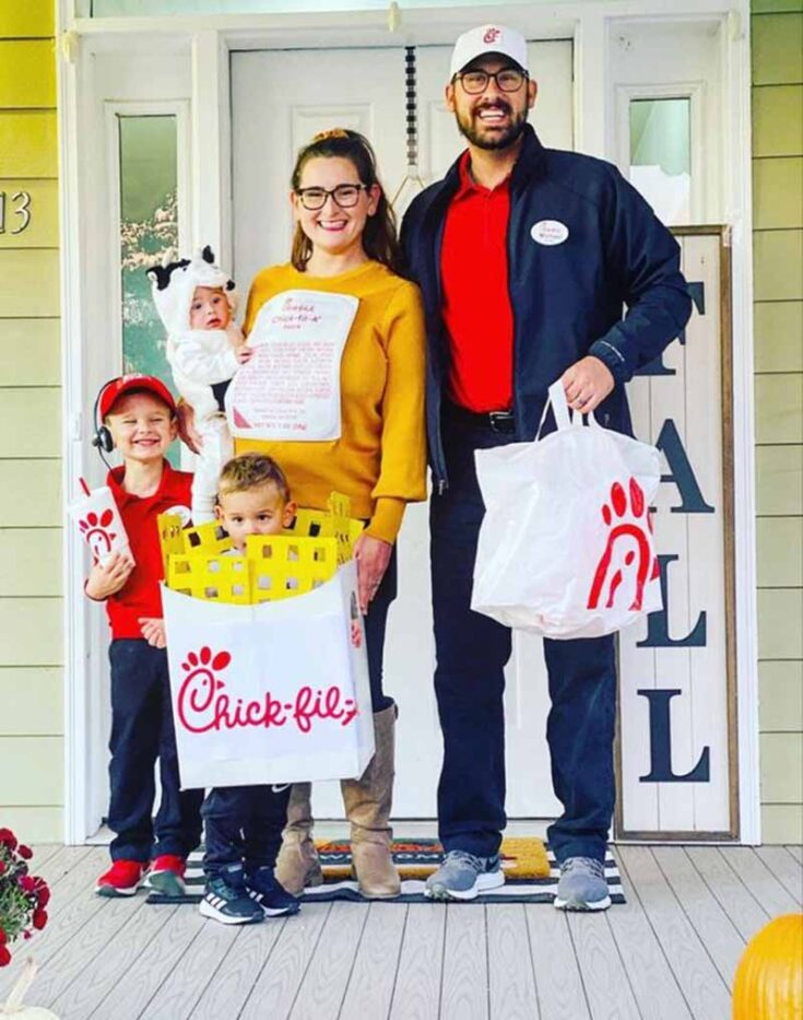 A family in Chick-fil-A-themed costumes stands on a porch decorated for fall—perfect inspiration for family costume ideas. The parents dress as Chick-fil-A workers while the kids are menu items: a nugget box, sauce packet, and cow.