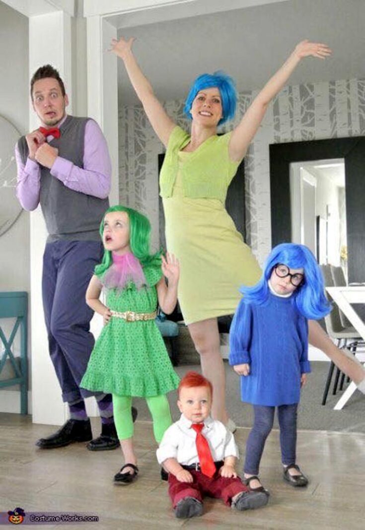 A family dressed as characters from the movie "Inside Out" poses together indoors, showcasing creative family costume ideas with colorful outfits and playful expressions representing each emotion from the film.