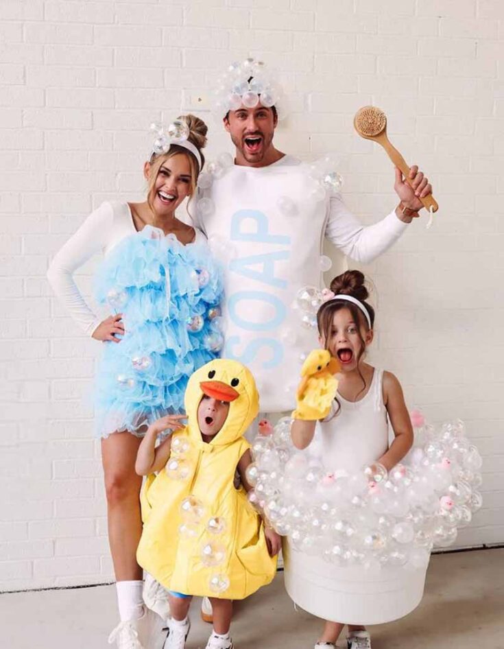A playful example of family costume ideas: the mom as a blue loofah, dad as soap with bubbles and a bath brush, one child as a rubber duck, and another as a bathtub complete with bubbles and a shower cap.