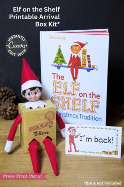 A plush Elf on the Shelf sits in a "Special Delivery for Oliver" box with the Elf on the Shelf Movie Night Printable Kit, near an "I'm back!" sign and book, all arranged on a wooden surface.