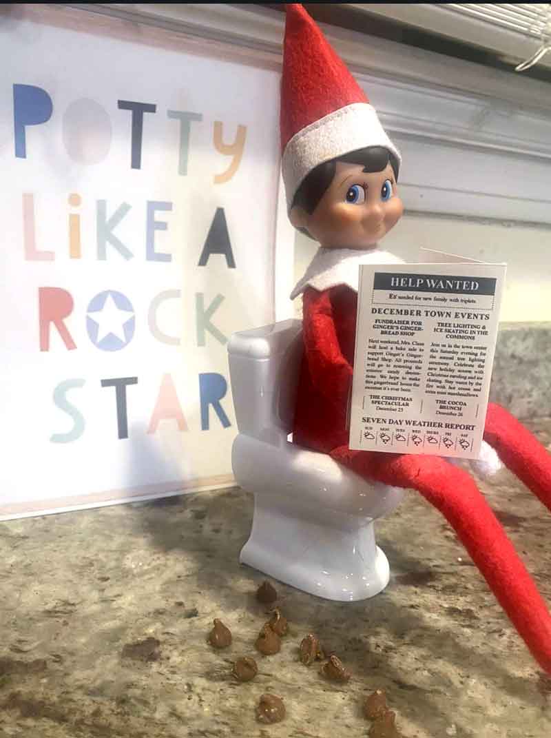 An Elf on the Shelf doll sits on a toy toilet by a "Potty Like a Rock Star" sign, holding a flyer—one of the funniest elf on the shelf poop ideas, complete with tiny brown "poop" props on the counter.