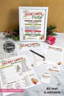 A set of template Canva (Copy) Secret Santa party printables on a marble surface, featuring sign-up sheets, questionnaires, and labels, with festive décor, a framed invitation, a pine sprig, and a small red gift box nearby.