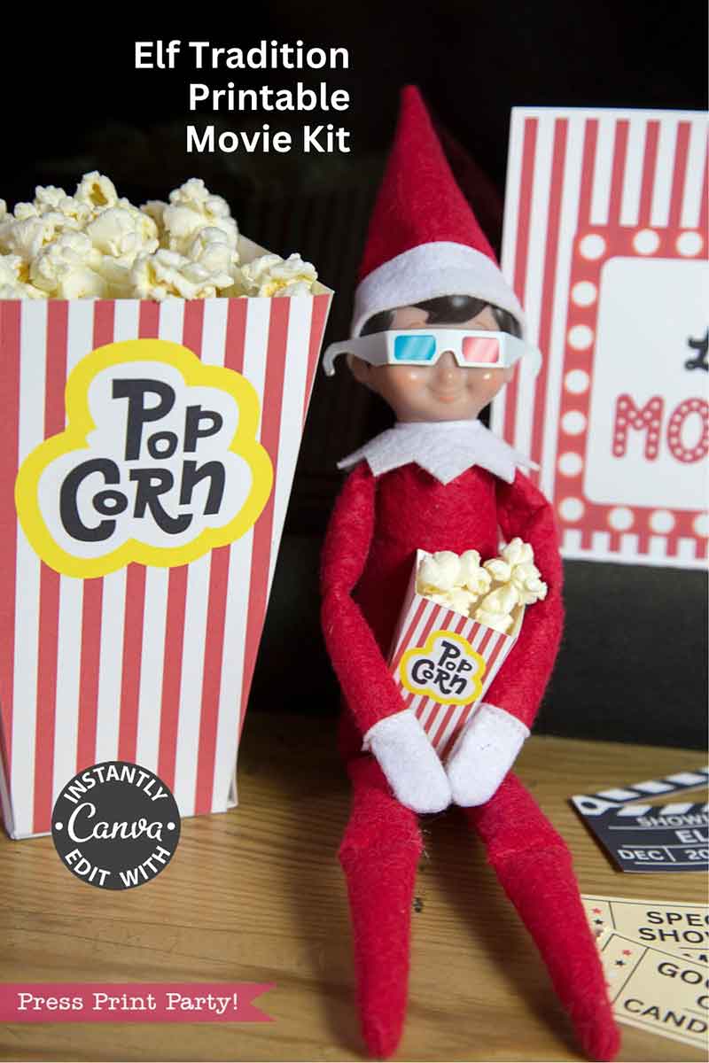 A toy elf doll in 3D glasses holds a popcorn box beside a large popcorn container, set for a movie night. Movie-themed decor and a sign reading “Elf on the Shelf Movie Night Printable Kit” are displayed in the background.