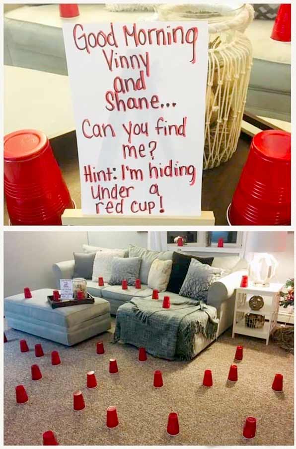 A note reads "Good morning Vinny and Shane... Can you find me? Hint: I'm hiding under a red cup!" Red plastic cups are placed all over a living room, including on furniture and the floor.