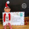 The Elf Arrival Postcard Printable features a plush Christmas elf in front of a festive postcard with a North Pole stamp, โElf Surveillanceโ badge, and kid-friendly note, surrounded by holiday decorations and berries.