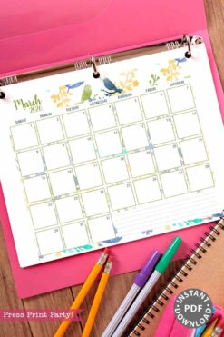A 2026 Calendar Set & Habit Tracker with watercolor floral designs is displayed in a binder on a pink folder, next to pens, pencils, and a spiral notebook. A label says