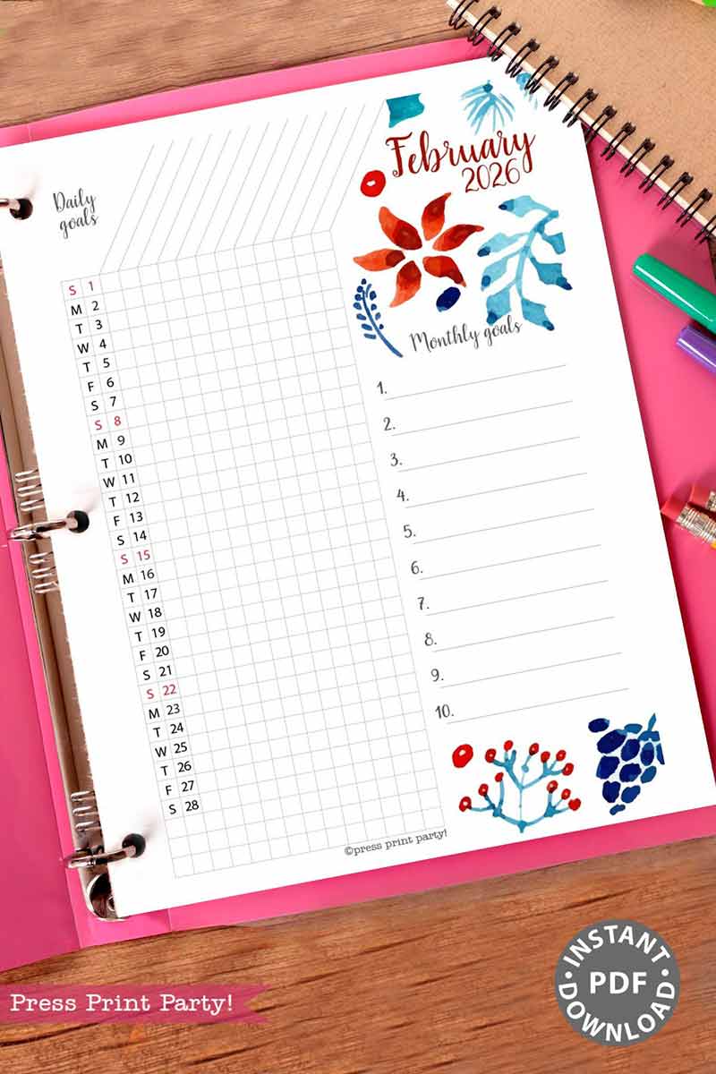 The 2026 Calendar Set & Habit Tracker features a February monthly goals planner page with watercolor floral designs, a daily goal tracker, and numbered goals list in a binder, with pens and a binder clip on a pink desk.