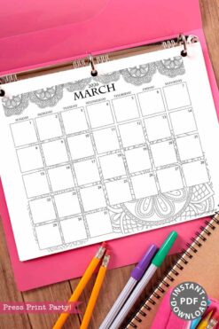 A 2026 Calendar Set & Habit Tracker in a binder, featuring watercolor floral designs, is displayed on a pink folder alongside a spiral notebook and three colorful pens or pencils.