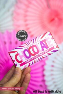 A hand holds a pink and white Valentine's Day chocolate bar reading "All you need is love and CHOCOLATE. HAPPY VALENTINE'S DAY!"—the perfect pairing with our Valentines Day Socks Wrap Printable.