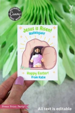 A hand holds the "Jesus Is Risen Easter Card for Mini Figurine," featuring a cartoon Jesus by an empty tomb. The card shows editable text: βJesus is Risen! Hallelujah! Happy Easter! From Katie.β Green leaves decorate the background.