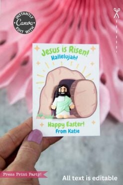 A hand displays the Jesus Is Risen Easter Card for Mini Figurine, showing Jesus emerging from the tomb with