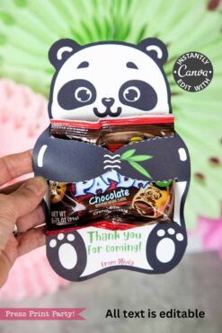 A hand holds the Panda Party Favors Treat Holder – Valentine & Party, featuring a smiling panda with two chocolate snack packs and a “Thank you for coming! from Olivia” sign. Perfect gift with Valentine’s Day socks; softly blurred background.