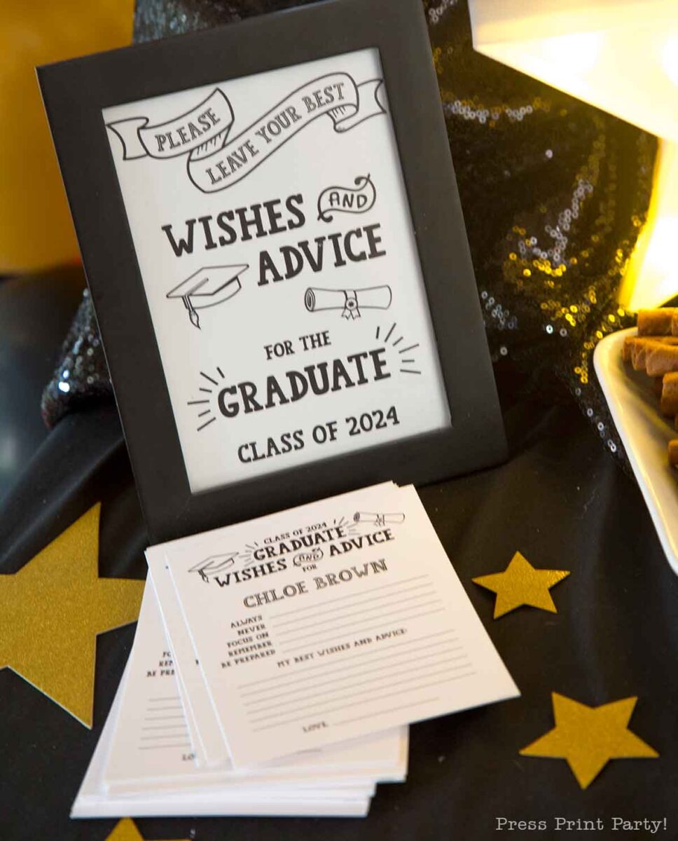 A framed sign reads βWishes and Advice for the Graduate Class of 2024β beside star-shaped dΓ©cor, cookies, and a stack of cards for guests to write notesβa perfect touch for a theater themed graduation party.