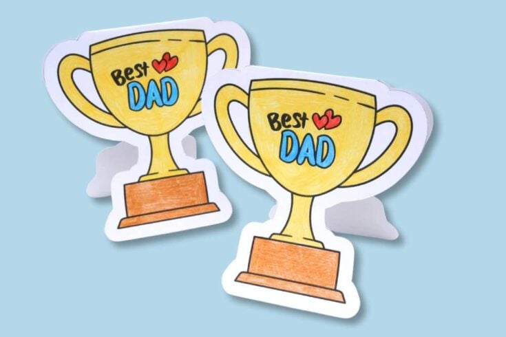 Two illustrated gold trophy cards with brown bases and the words "Best Dad" with red hearts, set against a light blue background.