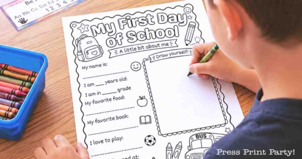 A child fills out a “My First Day of School” worksheet with crayons. The page has prompts for name, age, grade, favorite food, book, and a “Draw yourself” box. Colored crayons are in a blue container nearby.