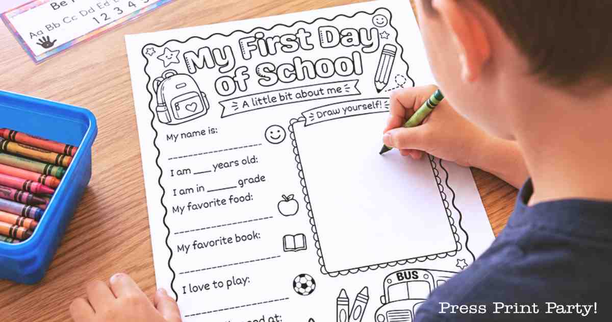 A child fills out a “My First Day of School” worksheet with crayons. The page has prompts for name, age, grade, favorite food, book, and a “Draw yourself” box. Colored crayons are in a blue container nearby.