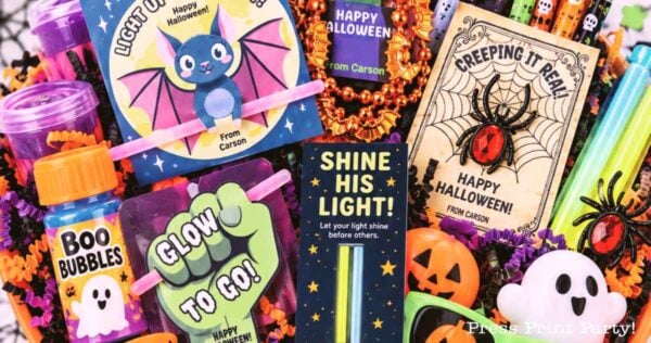 Colorful Halloween-themed gift basket featuring non-candy Halloween treats like glow sticks, decorated cards, bubbles labeled “Boo Bubbles,” a bat card, plastic spiders, pumpkins, and ghost items—all thoughtfully arranged in festive packaging.