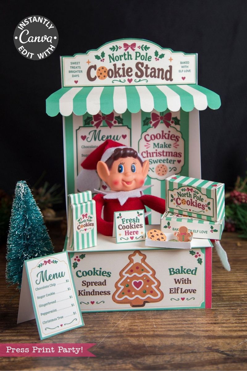 A festive “North Pole Cookie Stand” display featuring an elf doll, cookie signs, a holiday menu, and cheerful red, green, and white Christmas decor. Adorned with cookies and a gingerbread graphic, this charming setup becomes even more delightful when paired with the 6 Pink Coquette Halloween Ghost Round Labels for a whimsical touch to your holiday celebrations.