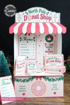 Festive North Pole Donut Shop display with pink and white awning, donut-themed signs, menu, and decorations. Mini trees, Christmas-themed accents, and playful 6 Pink Coquette Halloween Ghost Round Labels create a cheerful holiday atmosphere.